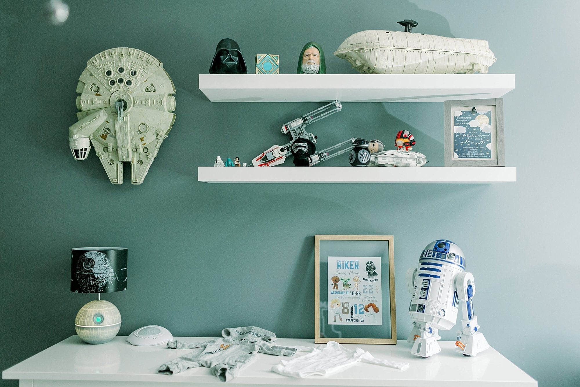 star wars nursery decor - hanging millennium falcon next to floating shelves filled with star wars figures