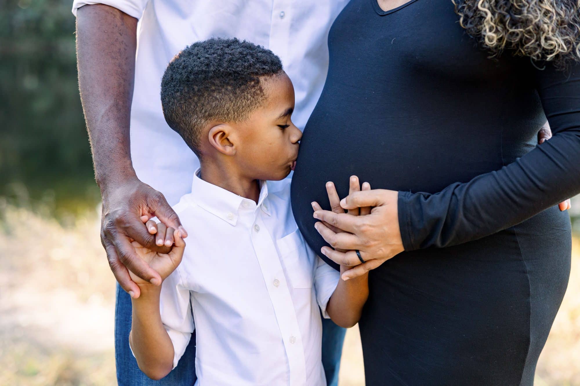 Little boy kissing mom's pregnant tummy