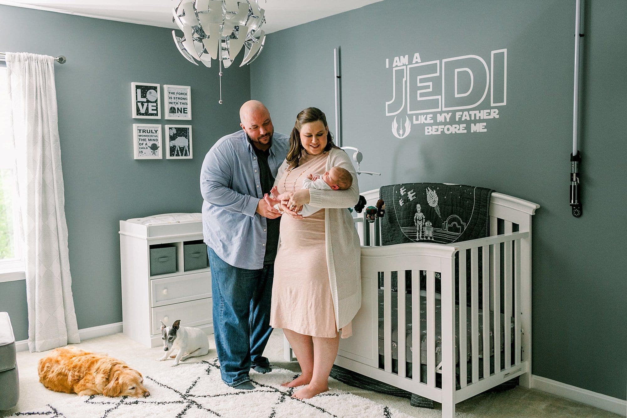 star wars nursery - parents holding baby in front of crib with puppy dogs laying on the floor near their feet